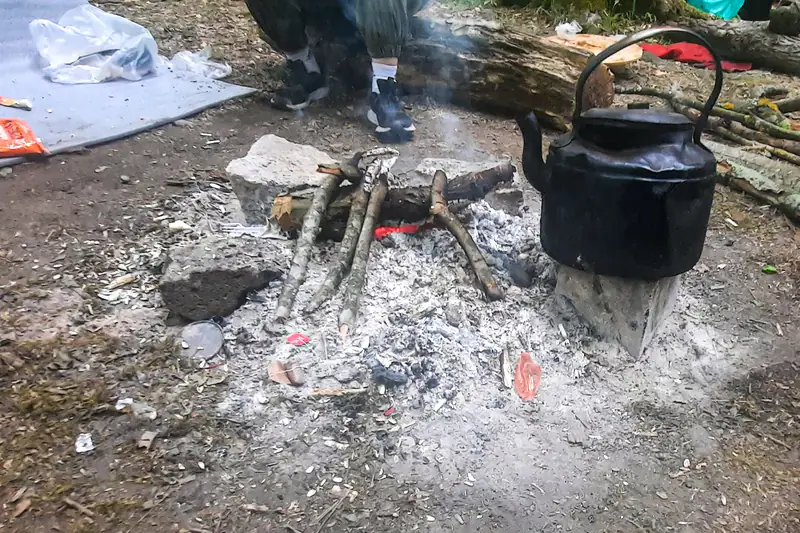 Harmaa tuhkakasa, jossa muutama kekäle, ja sen reunalla musta pannu.