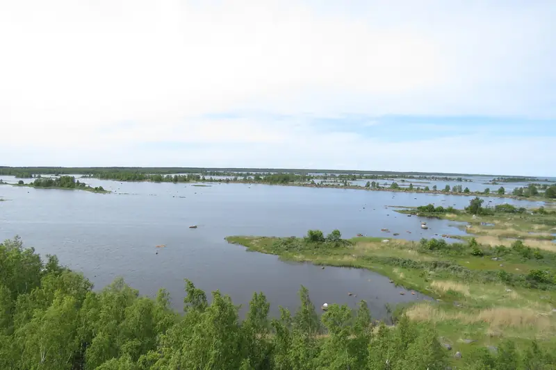 Matala saaristo ylhäältä: kapeita kivisiä niemiä ja luotoja tyynessä vedessä.