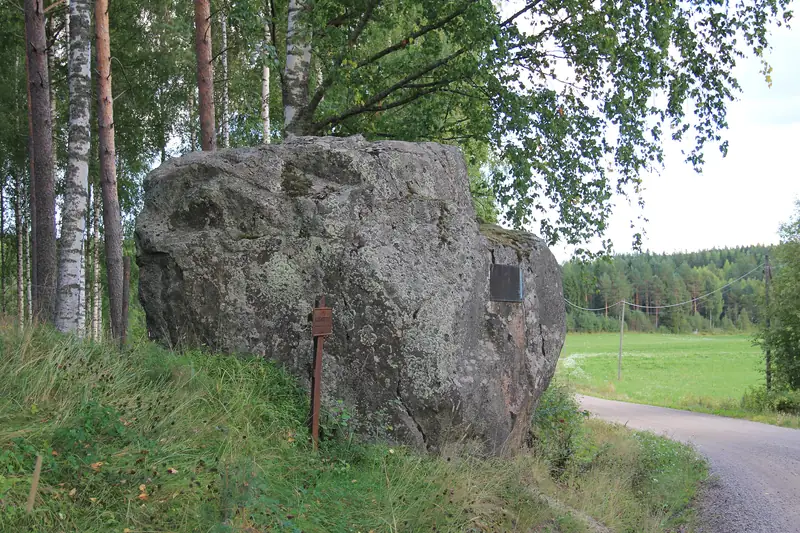 Iso yksinäinen kivi tienpientareella pellon laidassa.