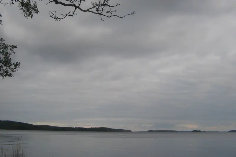 Järven yllä harmaa pilvikerros, joka on riveissä kulkevia litteitä, tummempia hattaroita.