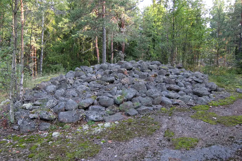 Matala, leveä kasa harmaita, suunnilleen samankokoisia kiviä kalliolla männikössä.